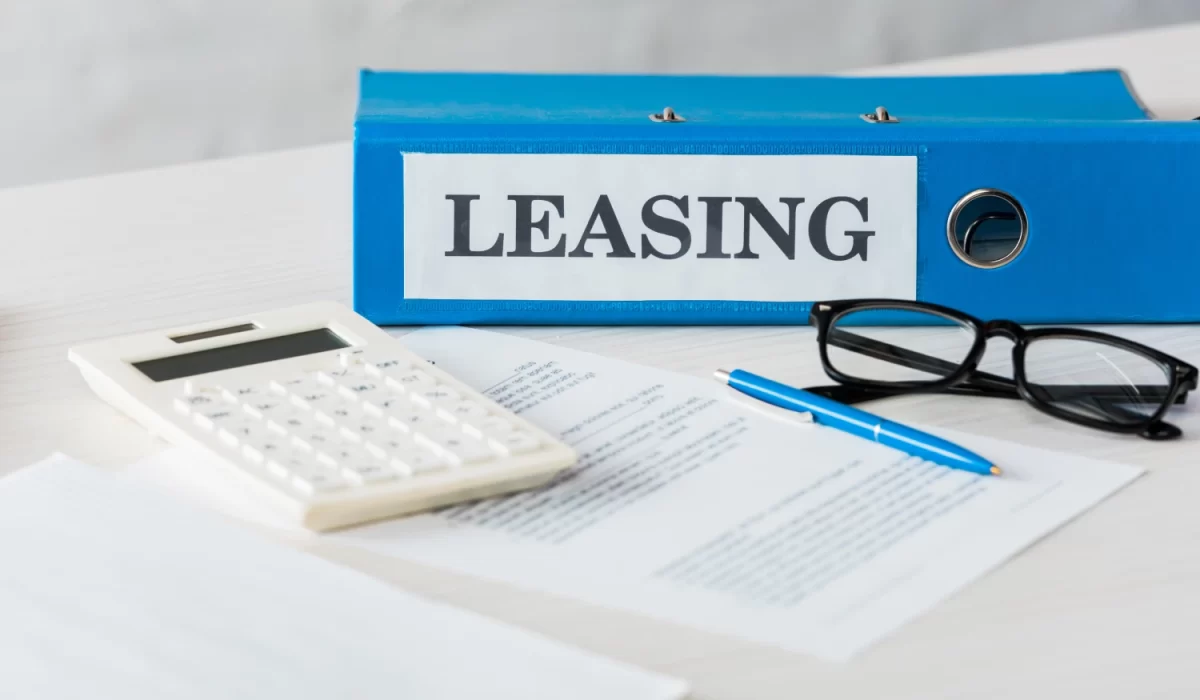 Escritorio con carpeta de leasing, calculadora y documentos, elementos esenciales para entender los aspectos legales y fiscales del arrendamiento financiero en México.